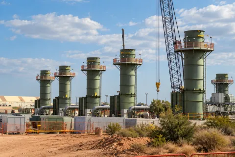 Industrial compute facility with processing towers and construction equipment, illustrating the Anthropic Nscale compute deal.