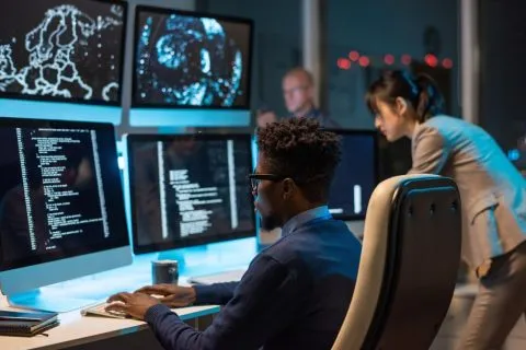 Cybersecurity analysts monitoring threat detection screens in a security operations center, illustrating Deepwatch layoffs 2025 and the company's increased investment in AI.