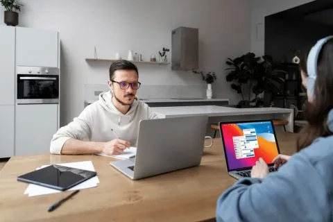 A graphic designer arranging a social media template on a laptop screen at a shared office desk