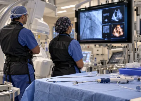 Cardiologists review imaging monitors and transcatheter heart valve repair equipment in a modern cardiac catheterization laboratory, illustrating PASCAL Precision tricuspid valve repair technology.
