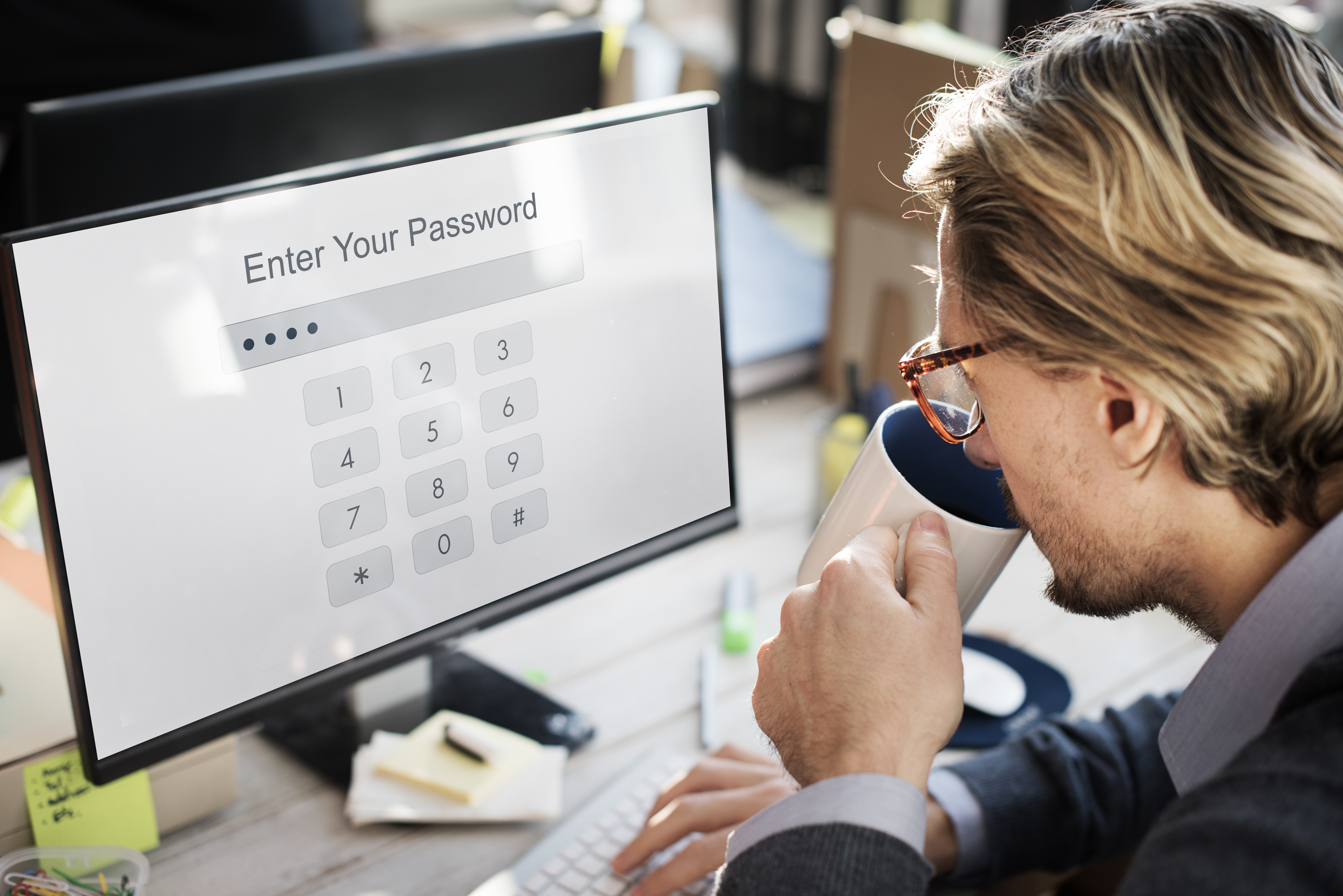 A person typing a password on a laptop with a password manager vault open on screen
